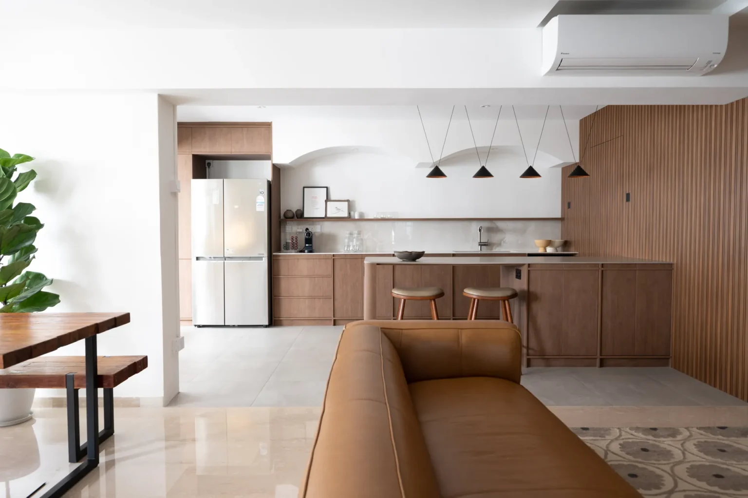 This image shows a warm, open family space where the kitchen and living area flow seamlessly through soft curves and natural materials.
